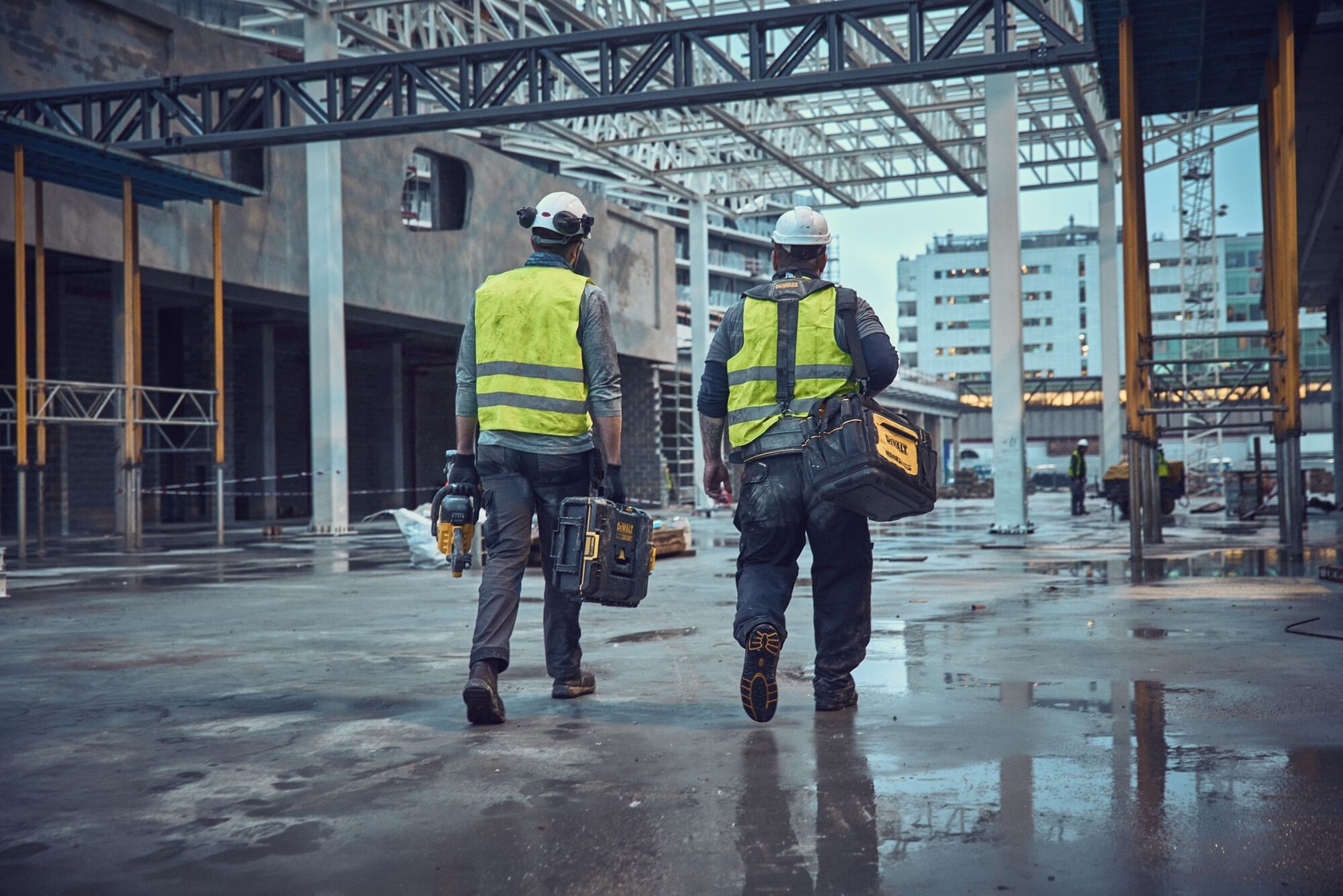 Two workers with DEWALT DWST1-75651, DWST40901-1, DCS691X2, DWST82990-1 tools at a construction site.